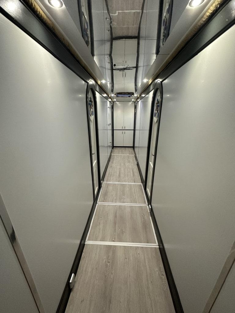 yacht interior corridor with white walls, grey wood flooring, and built-in storage compartments