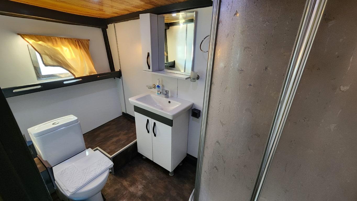 compact yacht bathroom with white toilet, vanity sink unit and glass shower door