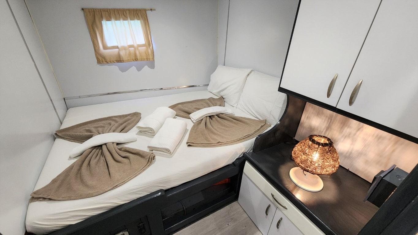 yacht guest cabin featuring twin beds with beige towel decorations and porthole window