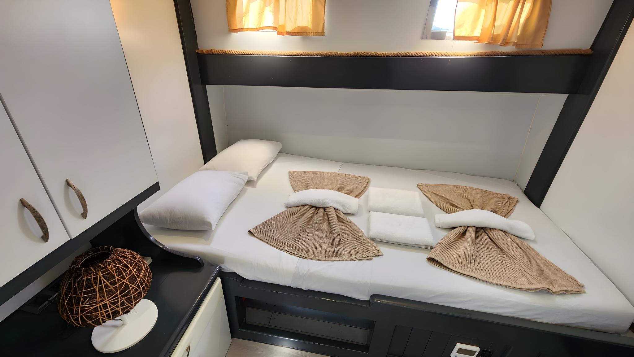 yacht guest cabin featuring double bed with white linens and brown towel decorations