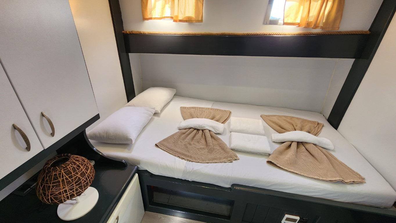 yacht guest cabin featuring double bed with white linens and brown towel decorations
