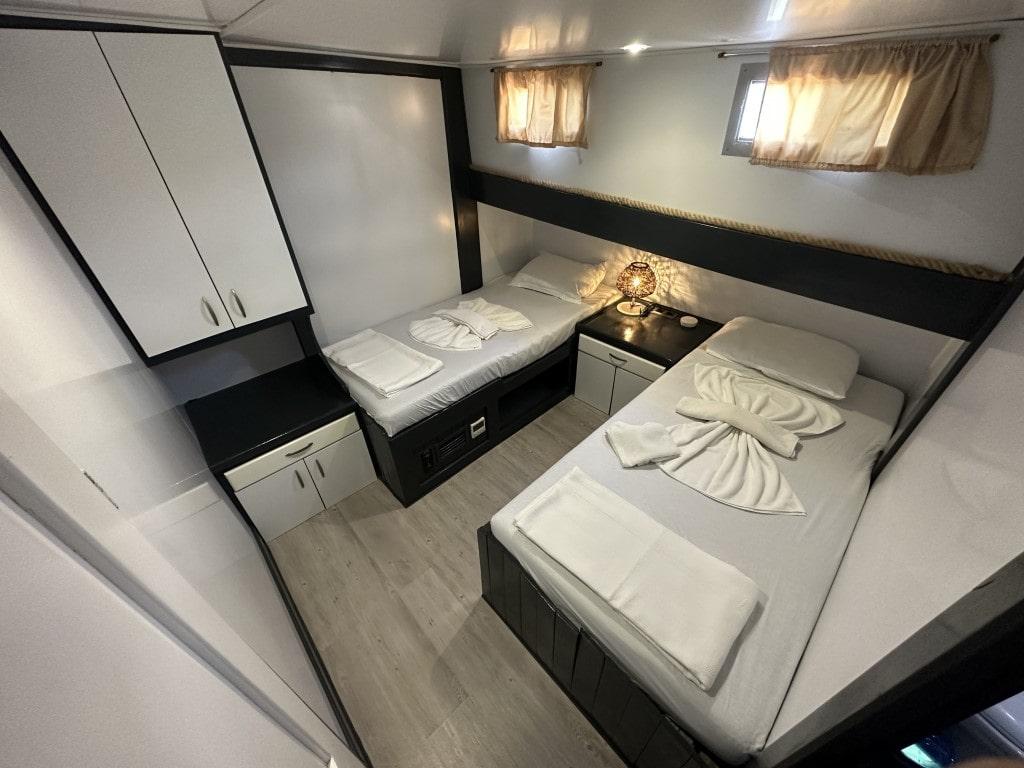yacht twin cabin with two single beds, overhead storage and portholes