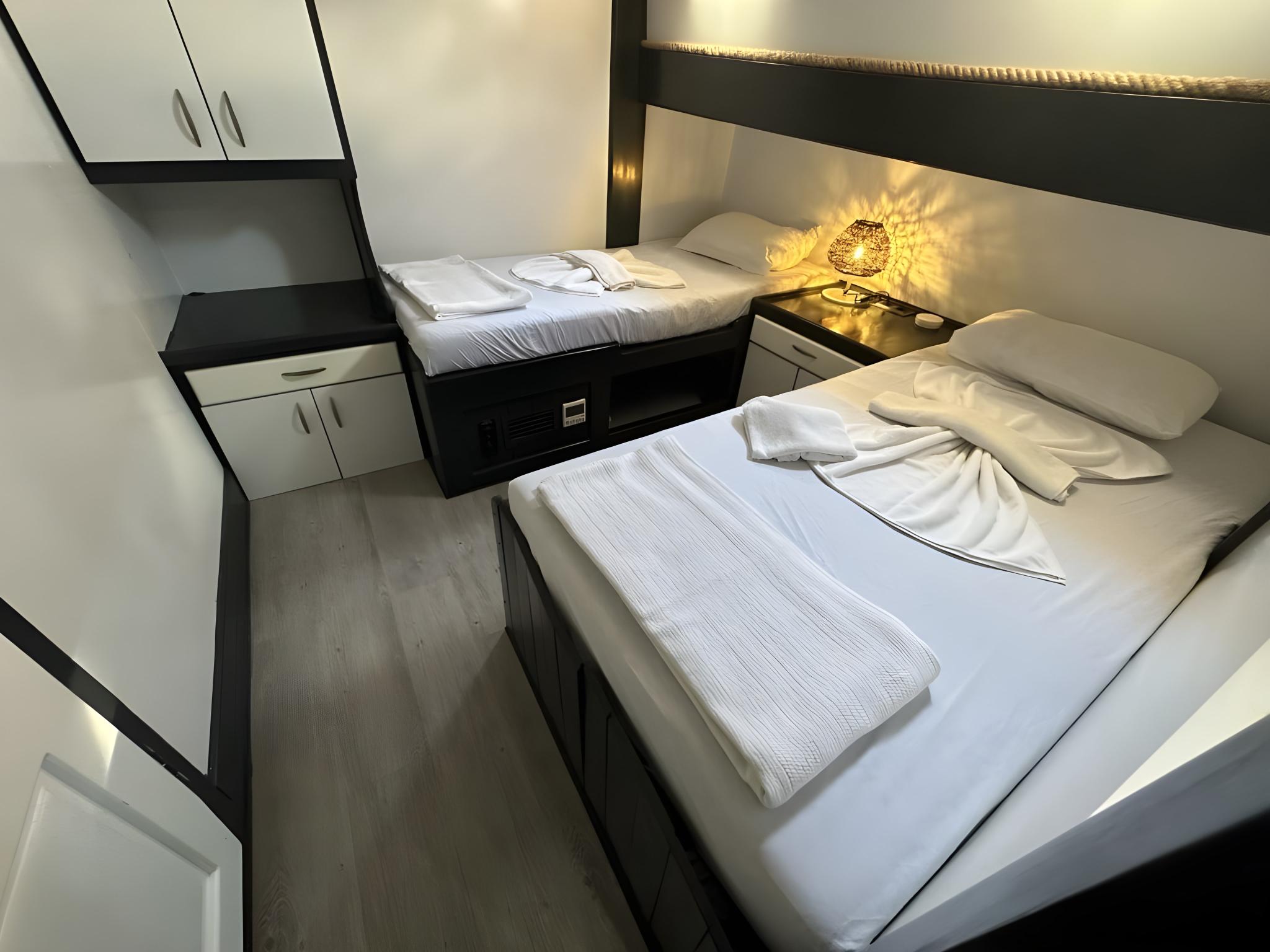 yacht twin cabin with two single beds, built-in wardrobes and bedside lighting