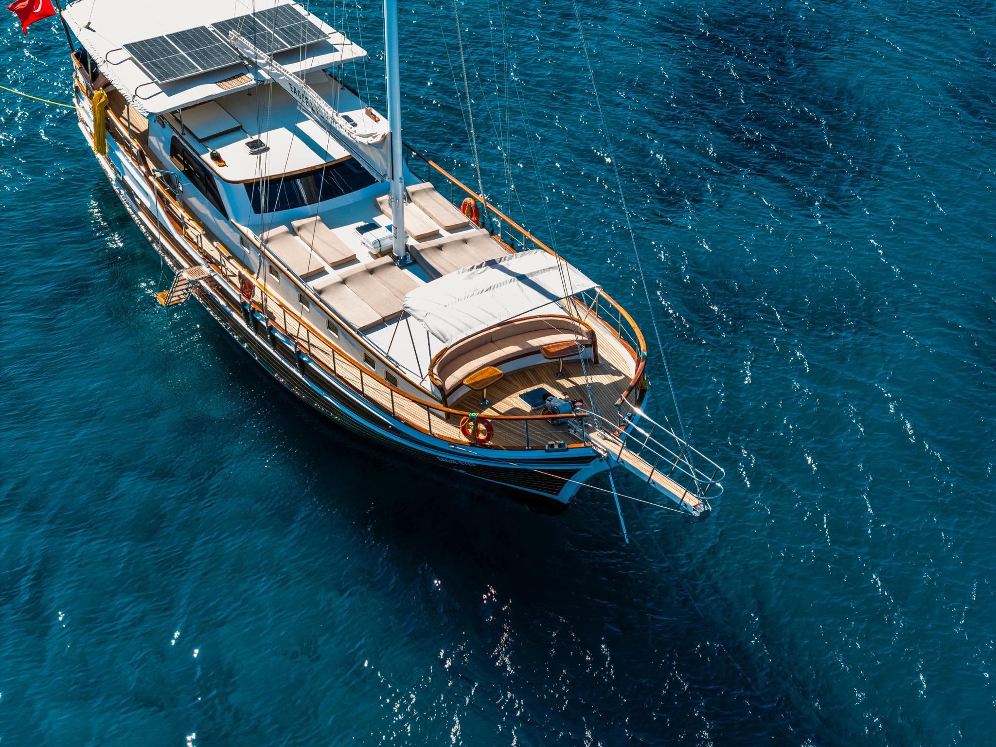 aerial view of traditional wooden gulet yacht with solar panels anchored in crystal blue Mediterranean waters