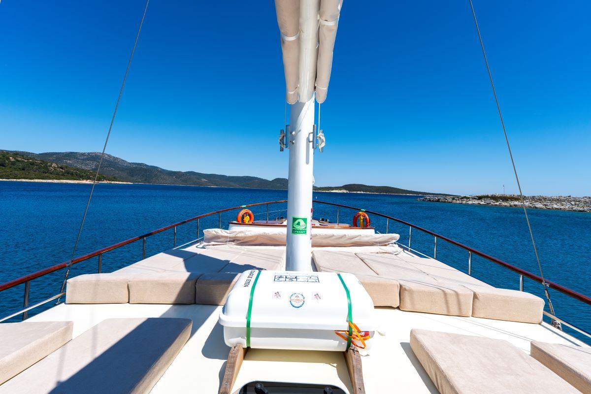 gulet bow deck with curved seating cushions around white mast and safety railings
