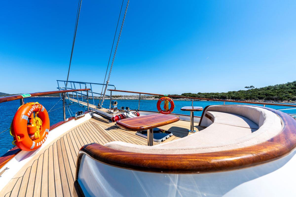 curved white seating area with teak decking and orange life rings on gulet deck
