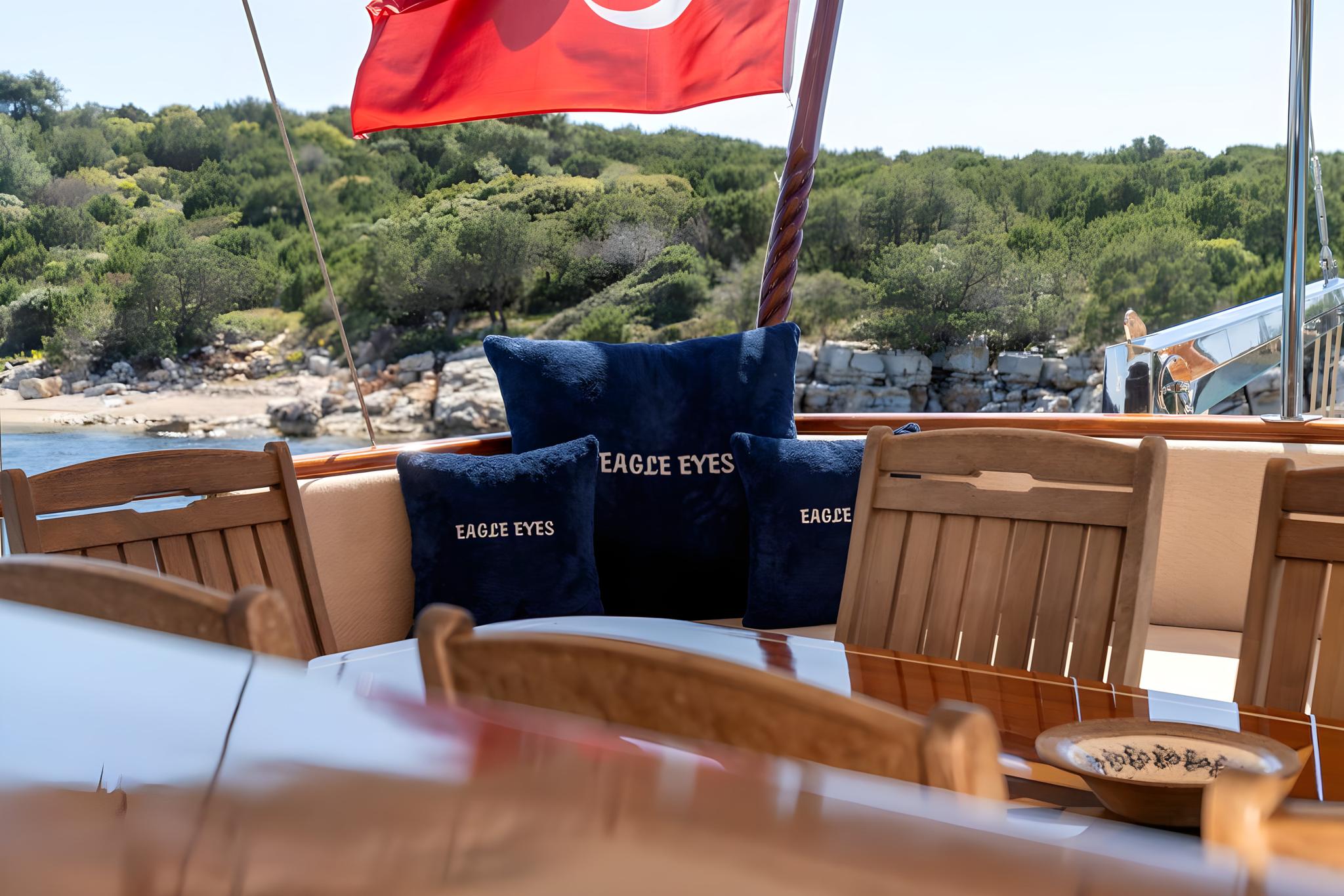 Gulet aft deck dining table with Eagle Eyes branded navy cushions and Turkish flag