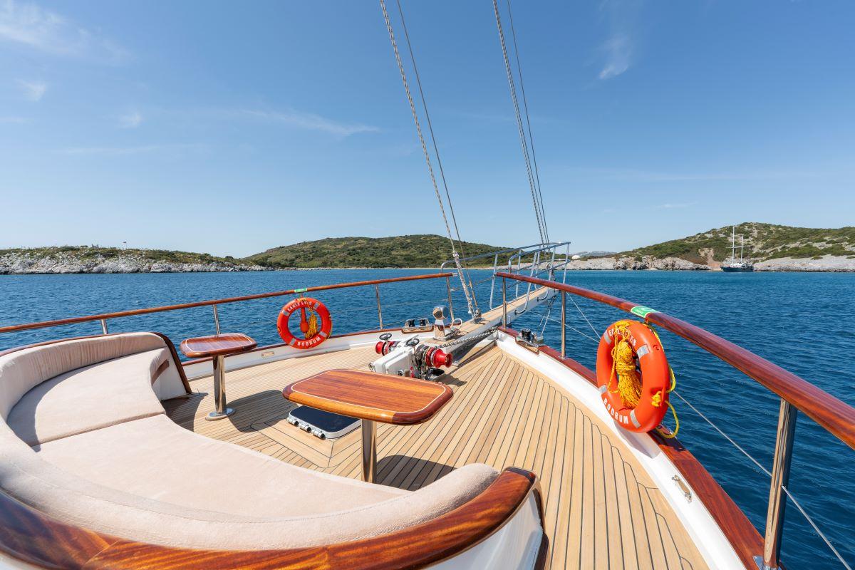 yacht forward deck with curved white seating, wooden table and teak decking