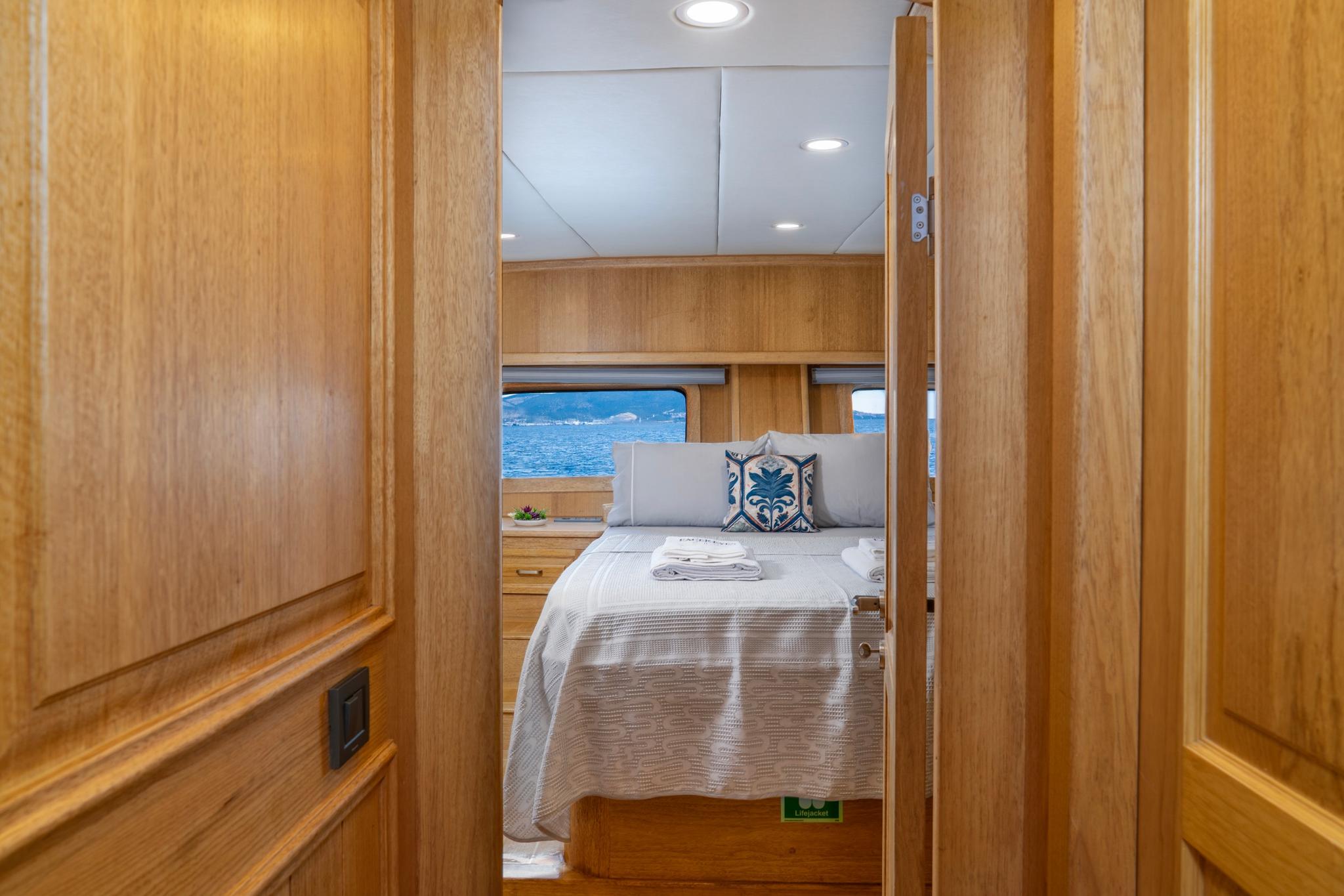 yacht guest cabin featuring double bed, built-in nightstands and panoramic ocean view windows