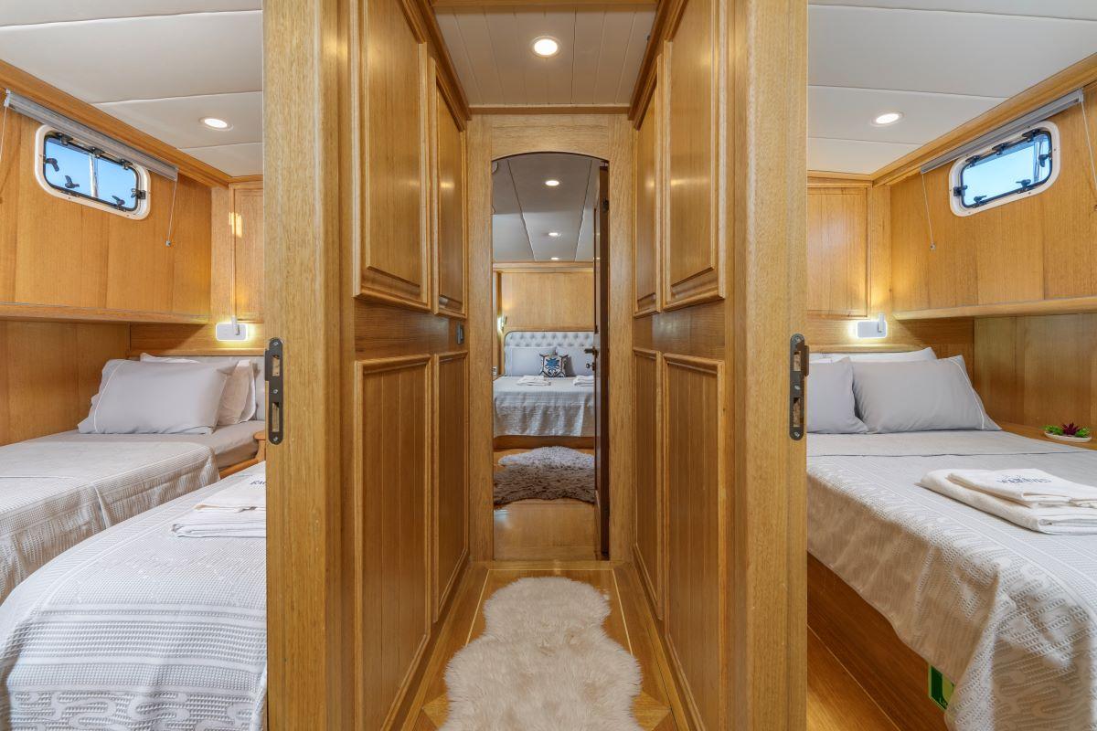 twin guest cabin interior with two single beds, built-in storage and ensuite bathroom entrance