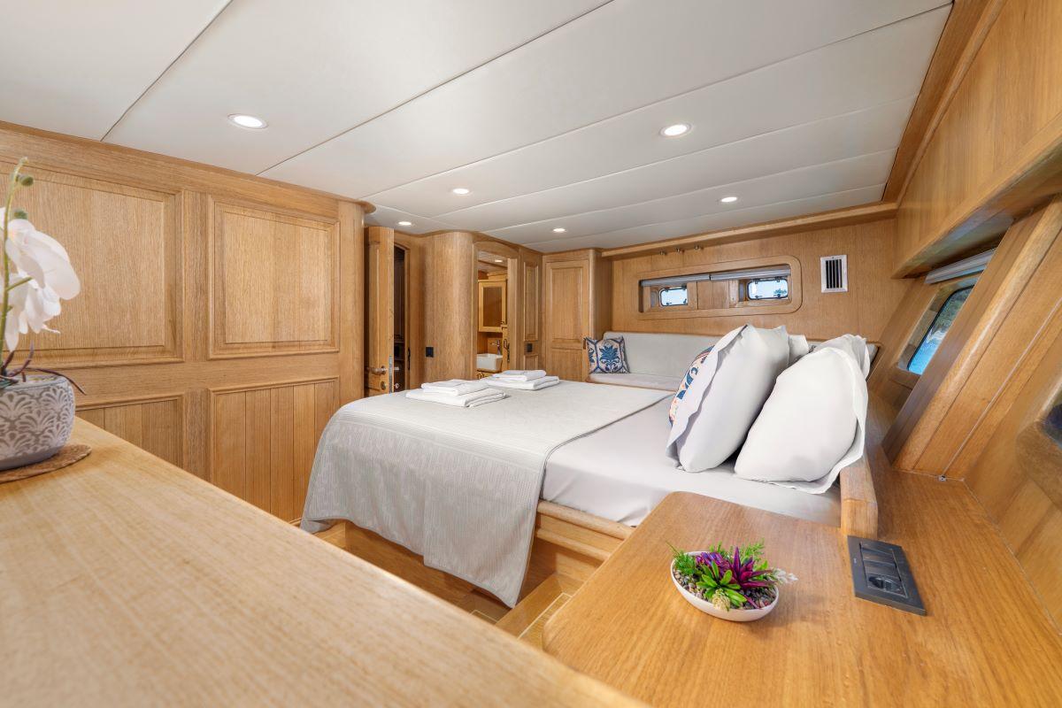yacht guest cabin with double bed, wooden paneling, and small porthole windows