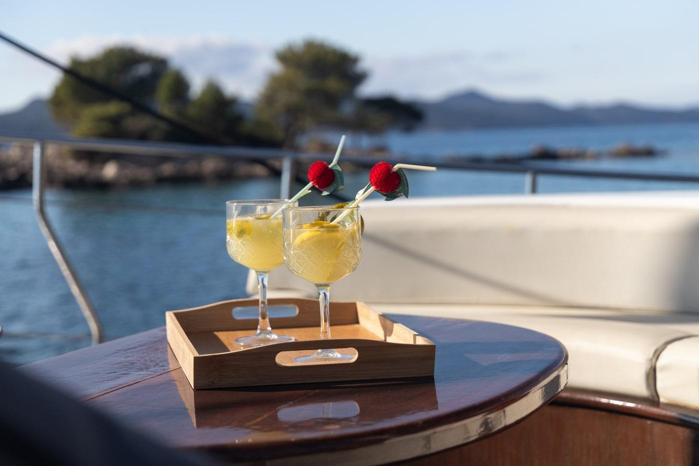 Two yellow cocktails with cherries served on wooden tray aboard luxury yacht
