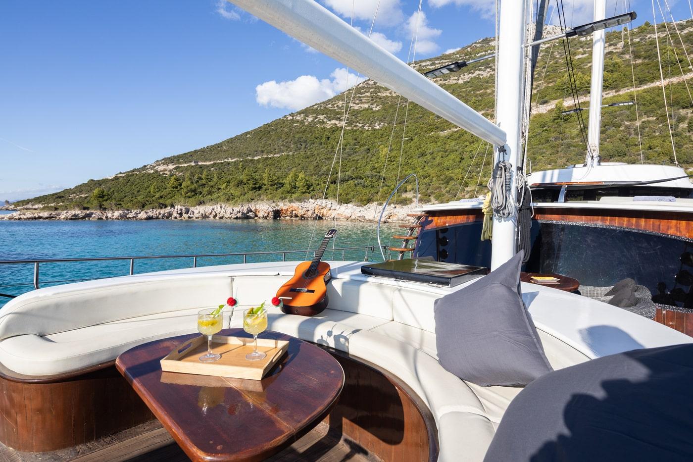 luxury gulet forward deck seating with cocktails guitar Mediterranean coastline