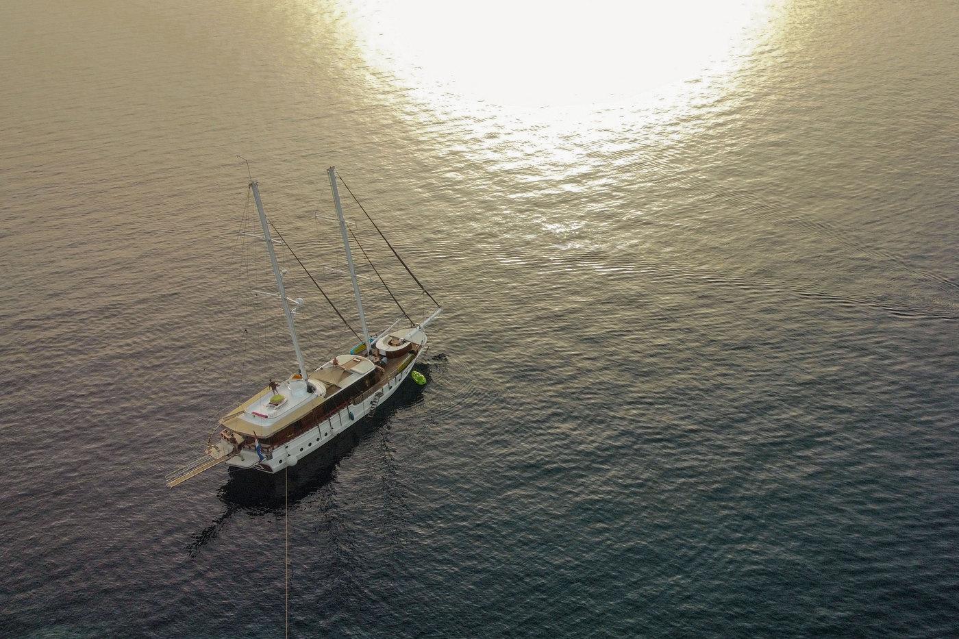 aerial view of traditional gulet yacht anchored in calm waters during golden sunset