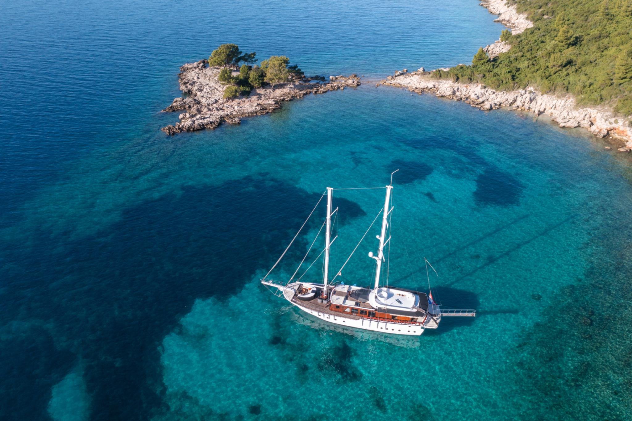 aerial view of traditional wooden gulet yacht anchored in crystal clear turquoise bay