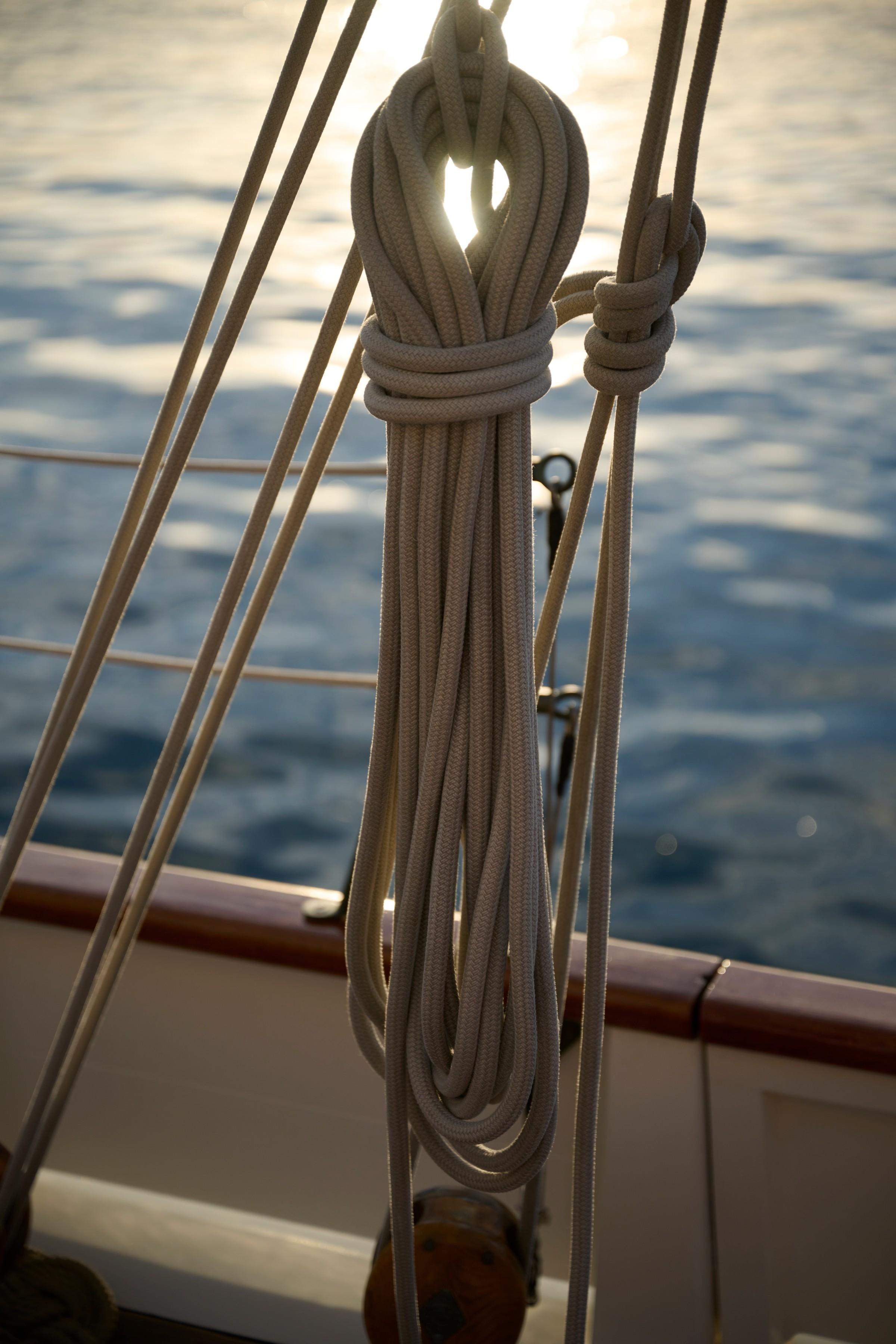 Neatly coiled white sailing ropes tied to gulet rigging with calm blue sea in background