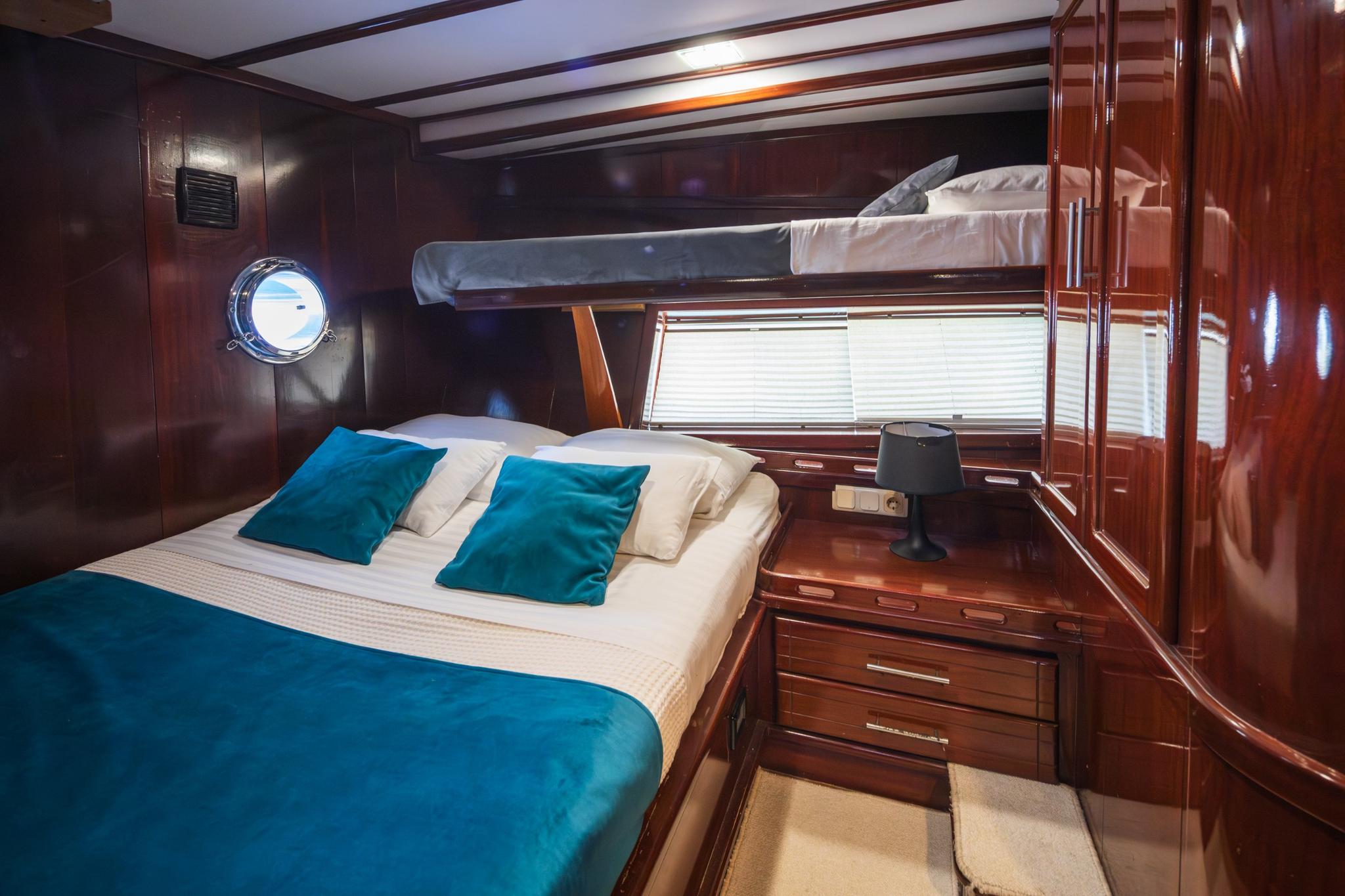 yacht guest cabin featuring double bed with teal bedding and upper bunk berth