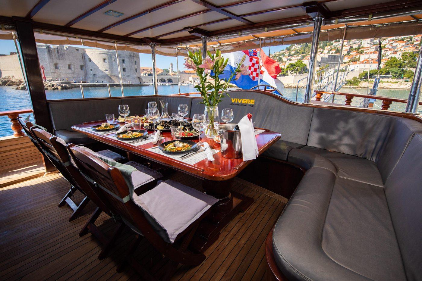outdoor dining table with prepared meals, wine glasses and Croatian flag aboard gulet