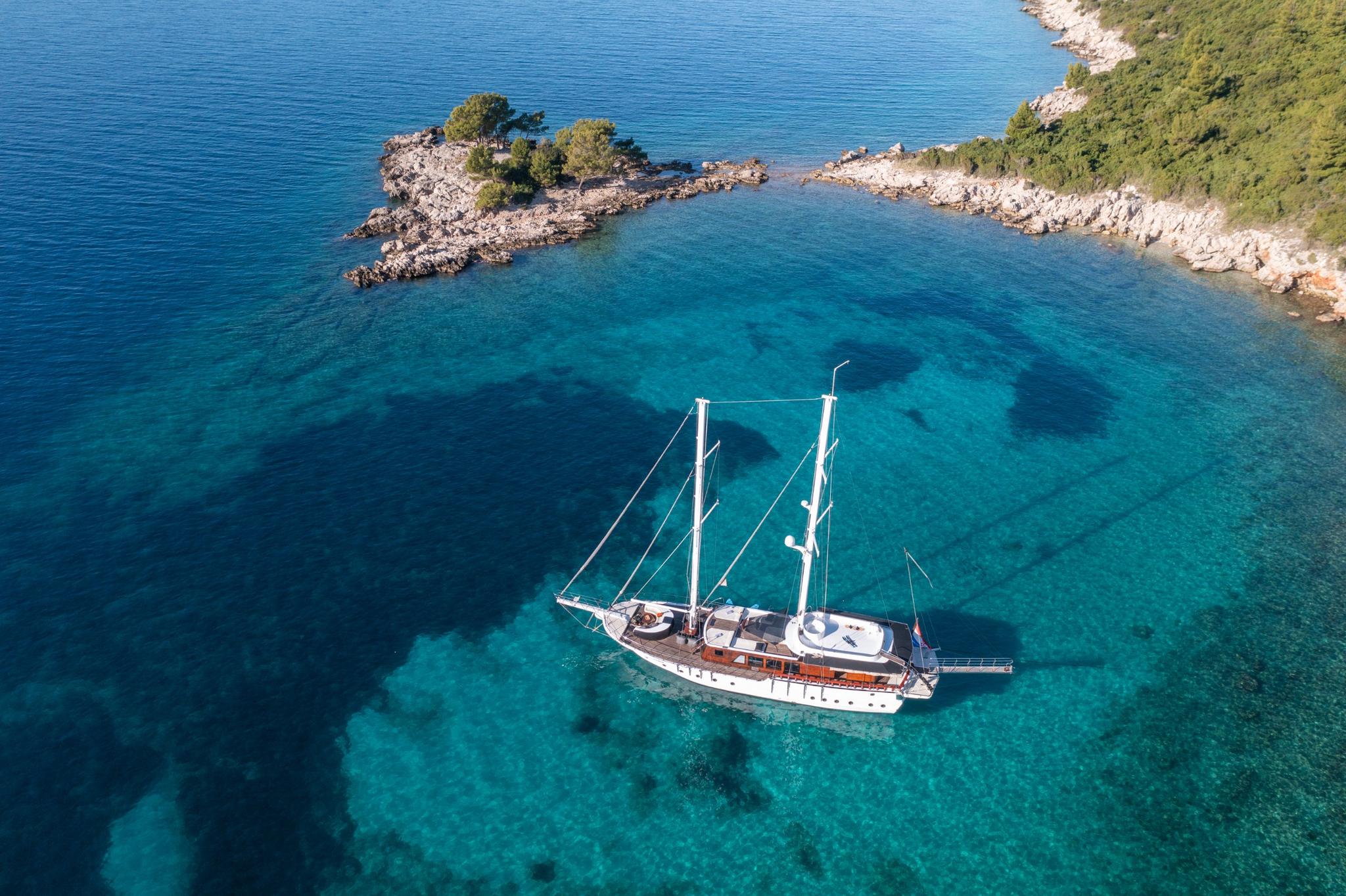 aerial view of traditional gulet yacht anchored in crystal clear turquoise Mediterranean bay