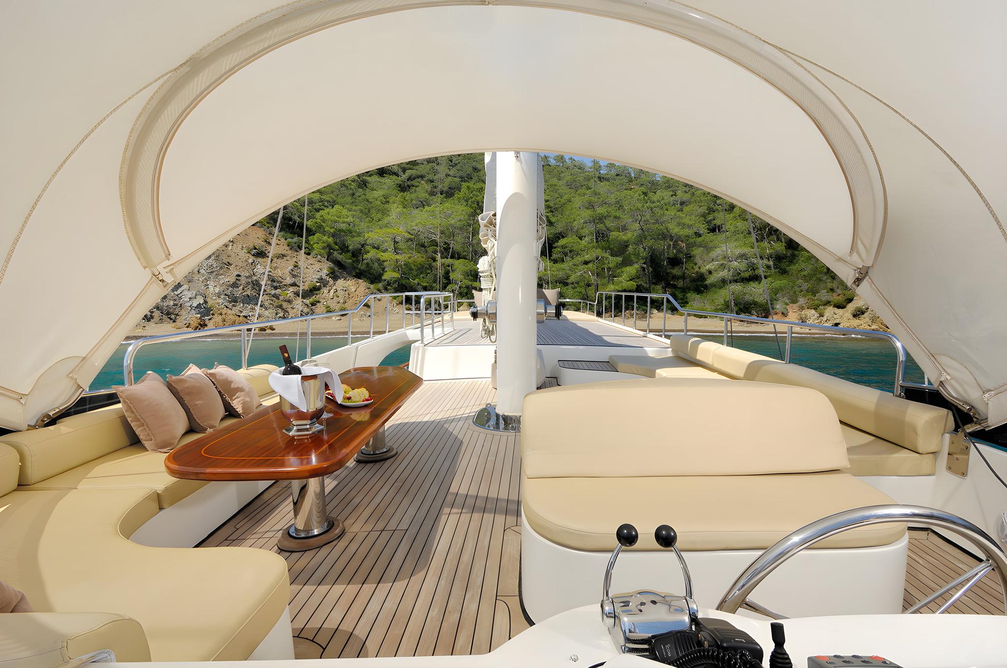 yacht aft deck with cream leather seating, teak flooring, and fabric canopy overhead