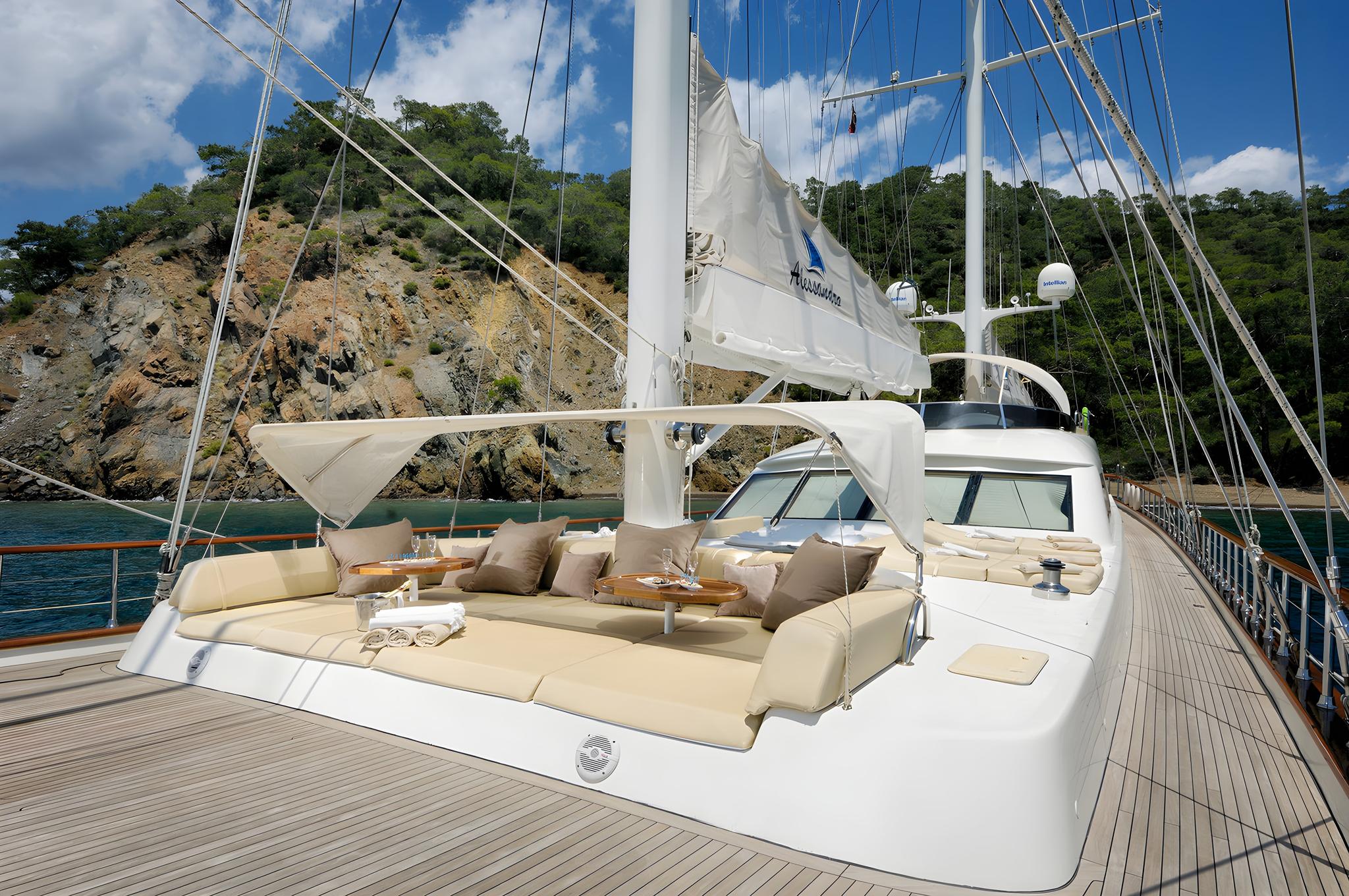 luxury yacht forward deck with sunken seating area, cream cushions, teak decking, white mast and rigging