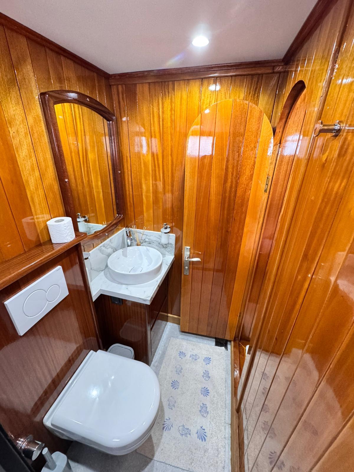 yacht guest bathroom featuring polished wood paneling, round vessel sink, and nautical-themed floor mat
