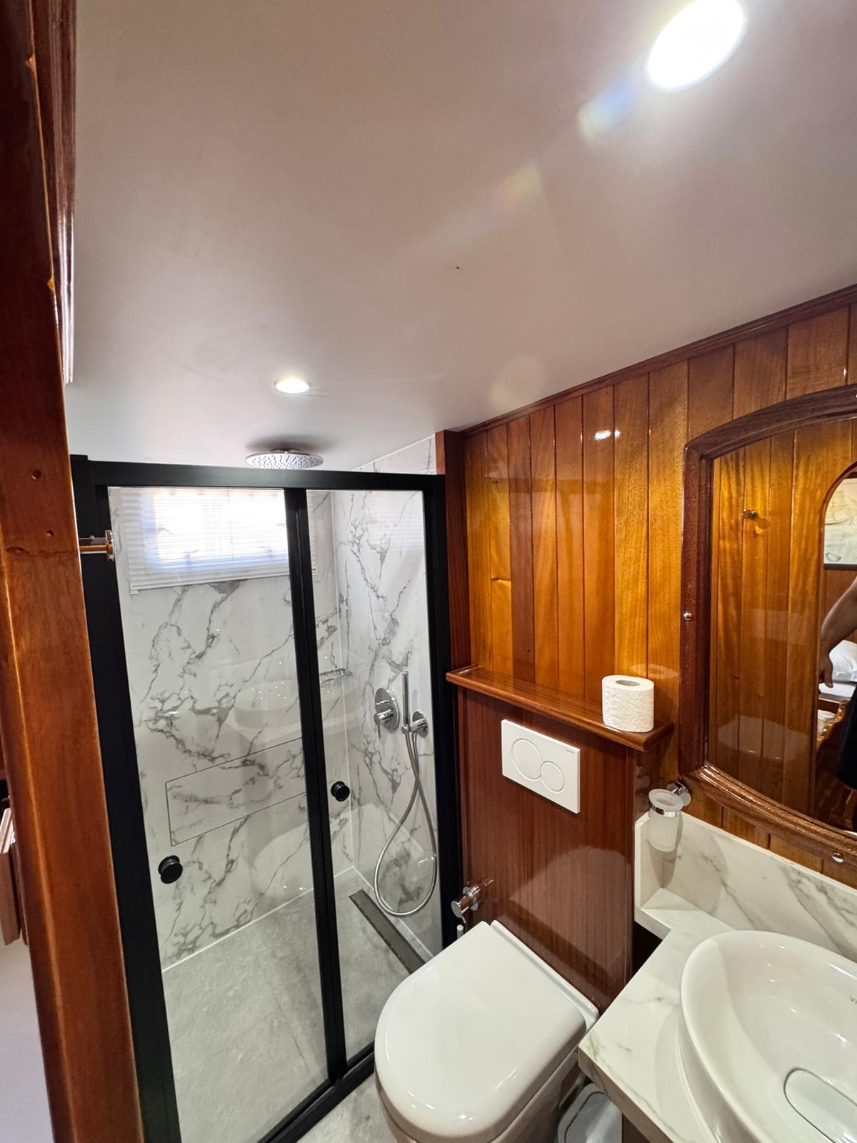 yacht bathroom featuring marble shower enclosure, toilet, and rich wood paneling throughout