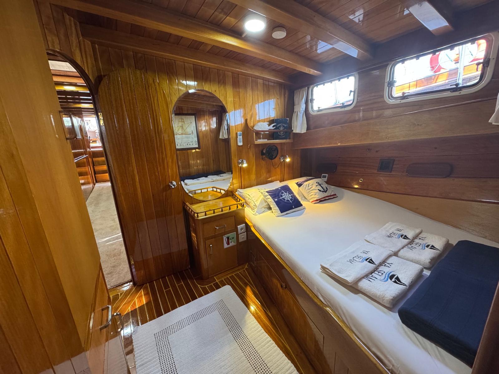 wooden guest cabin interior with double bed, nautical pillows, and built-in storage