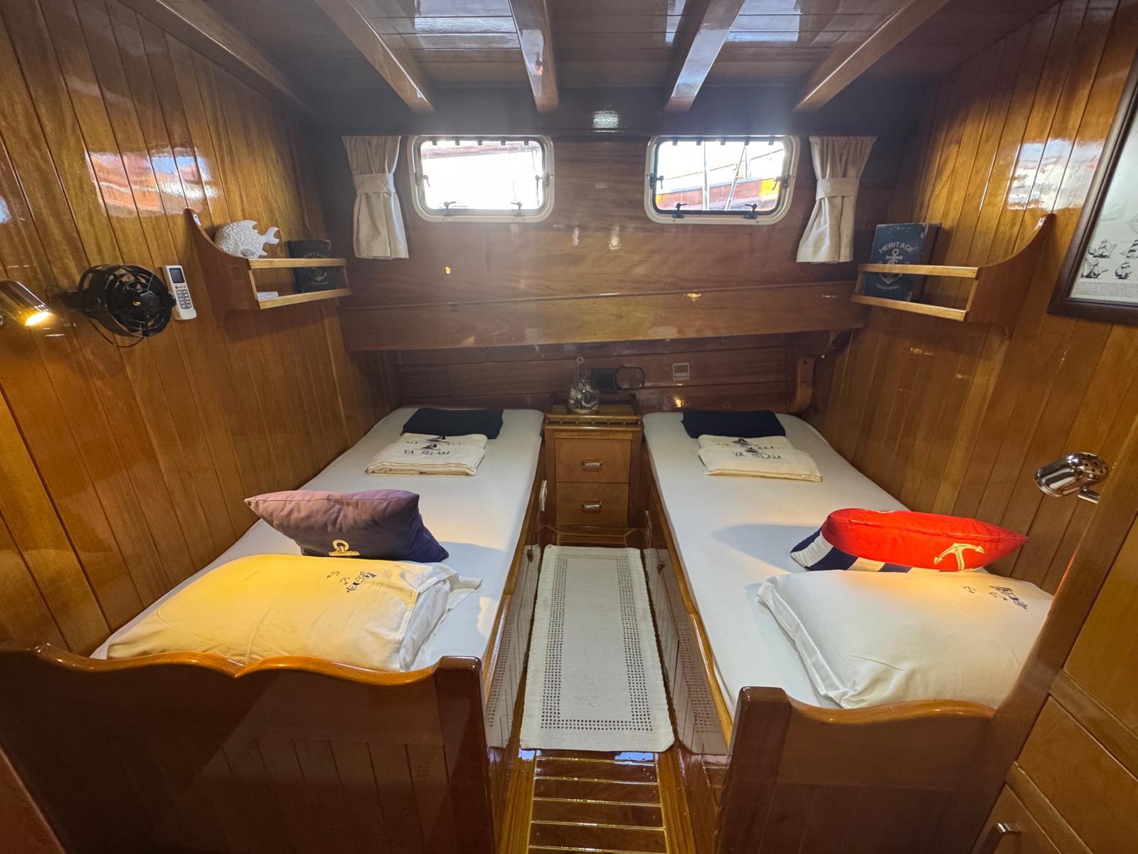 twin guest cabin with two single beds, wooden paneling, portholes and nautical themed pillows