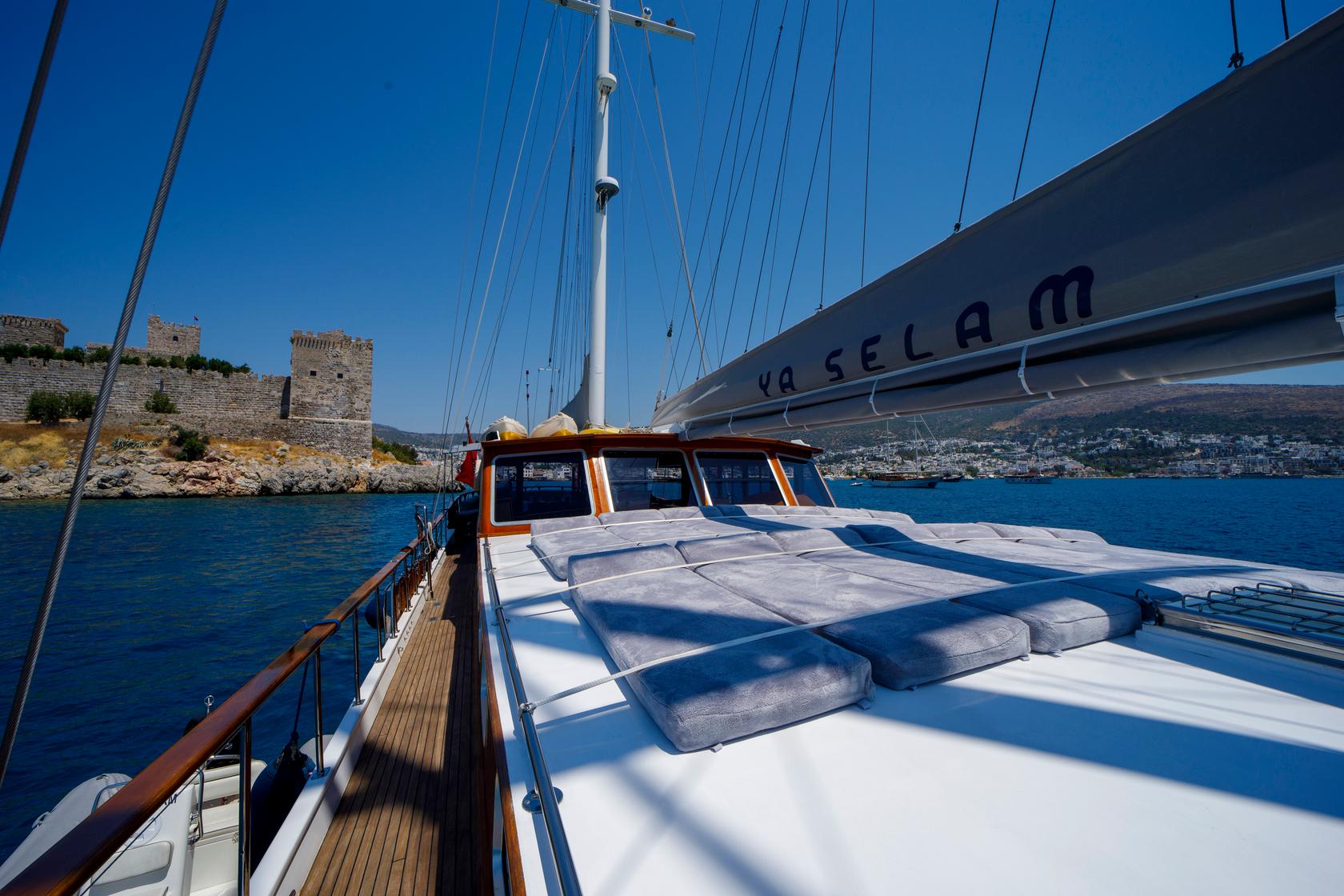 gulet bow sun deck with white cushioned loungers and traditional wheelhouse with orange trim