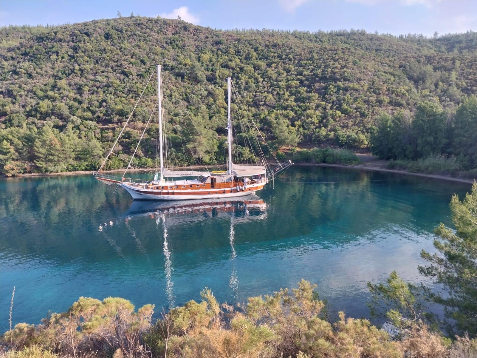traditional wooden gulet yacht anchored in secluded turquoise bay surrounded by forested hills