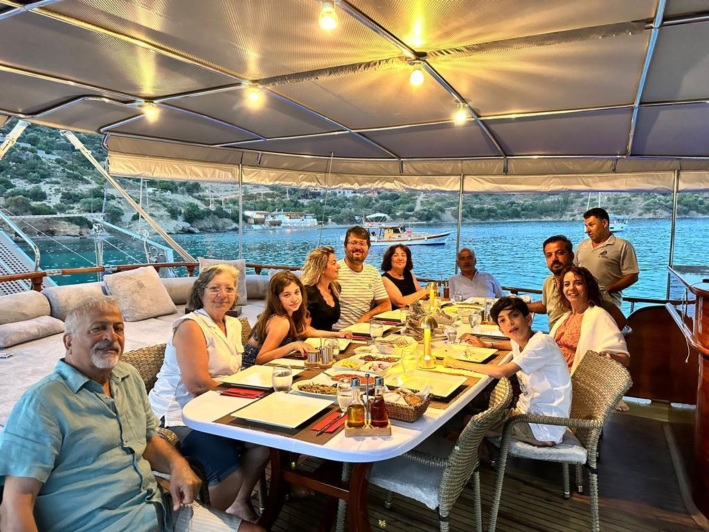 Family enjoying dinner together at dining table on yacht aft deck with food and drinks