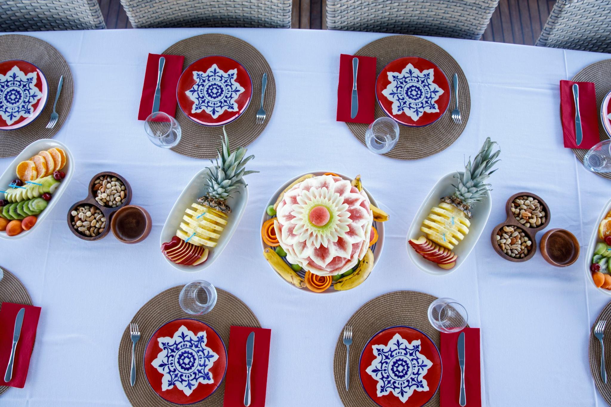 yacht dining table with decorative watermelon carving, fruit platters, and ornate Turkish-style plates