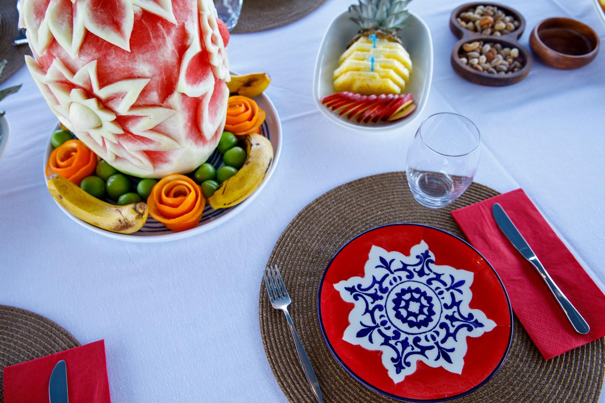 luxury yacht dining table with carved watermelon centerpiece, fresh fruit platter and formal place settings