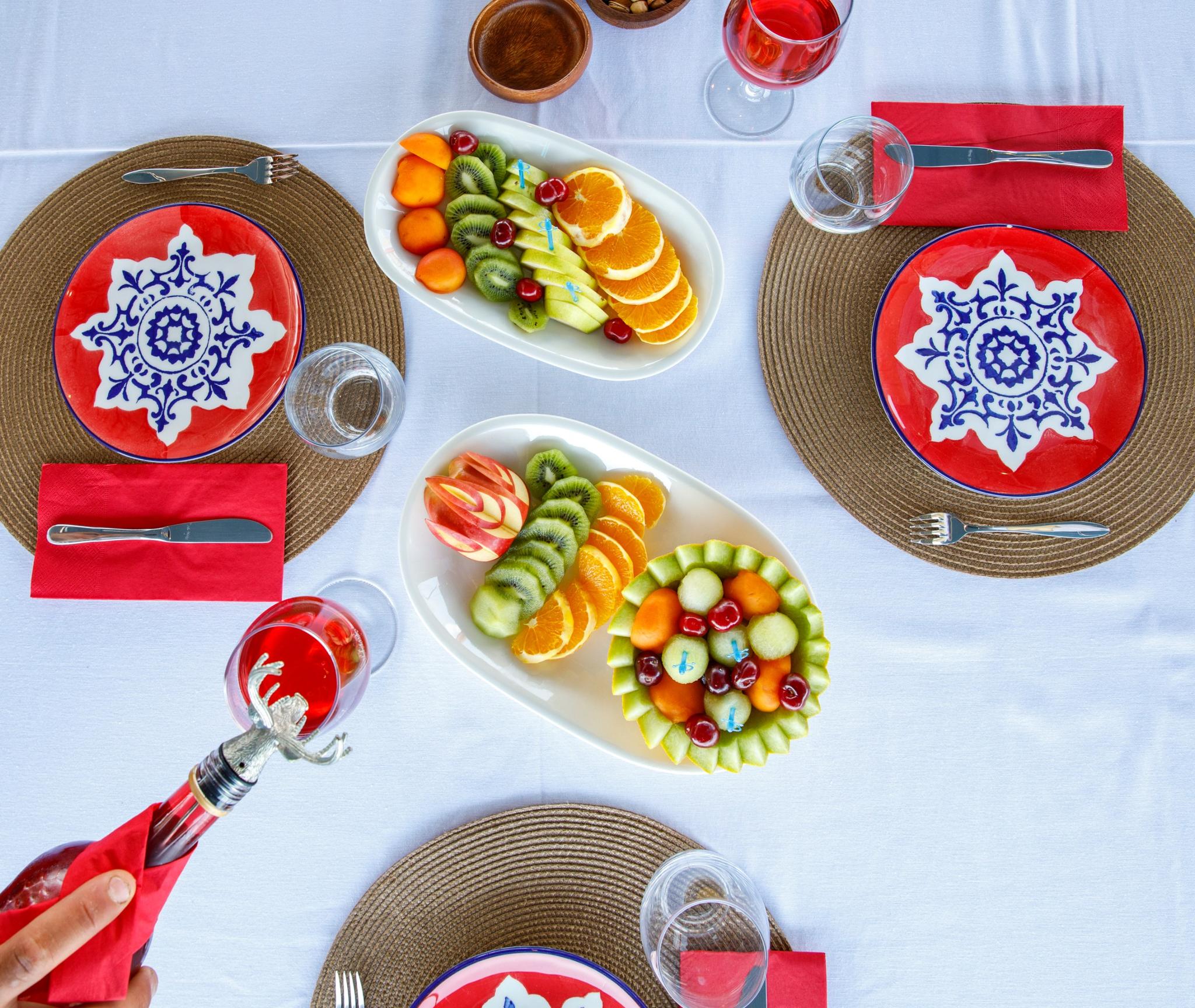 luxury yacht dining table with decorative plates, fresh fruit arrangements and red wine glasses
