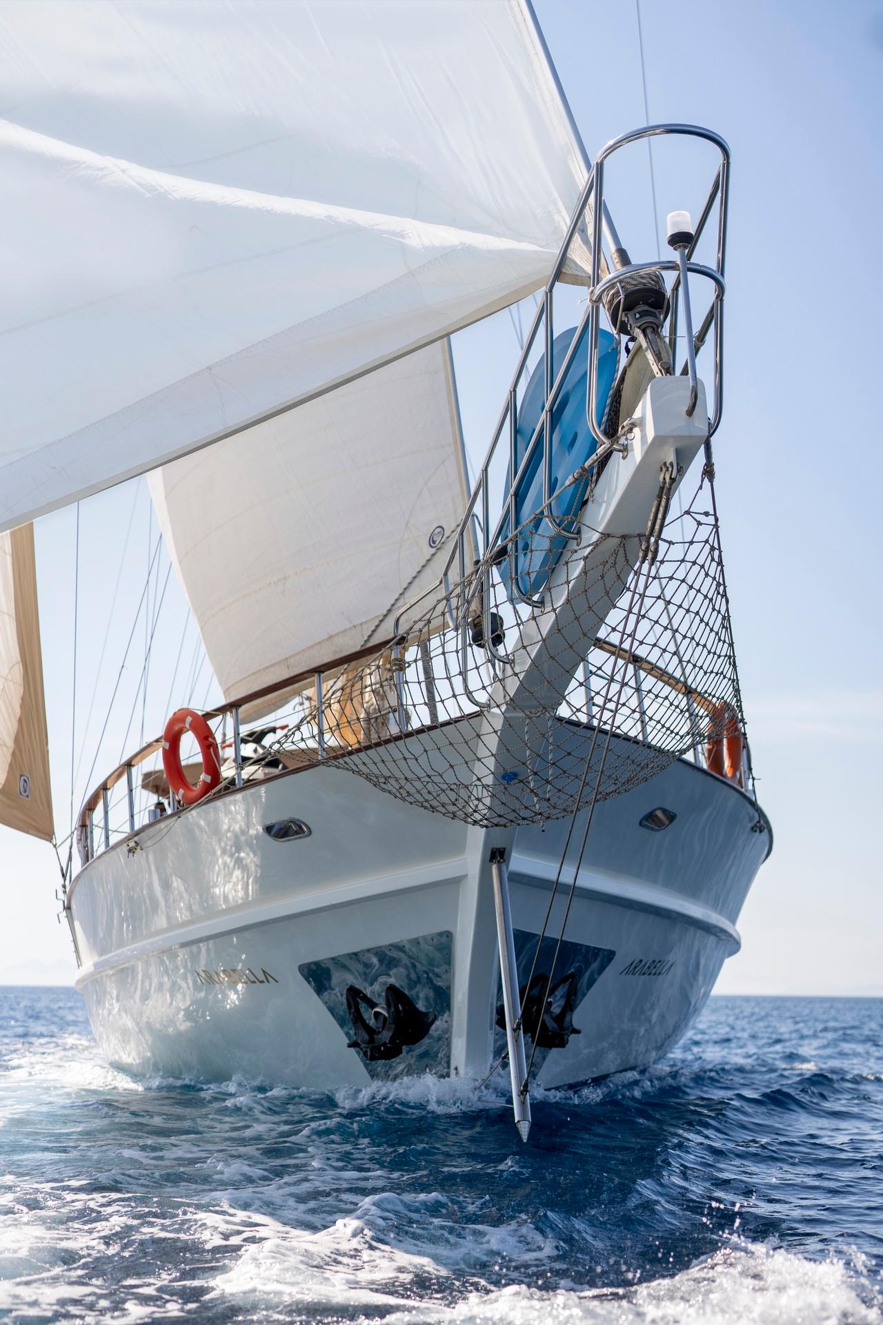 White traditional gulet yacht sailing with full sails deployed on blue ocean water