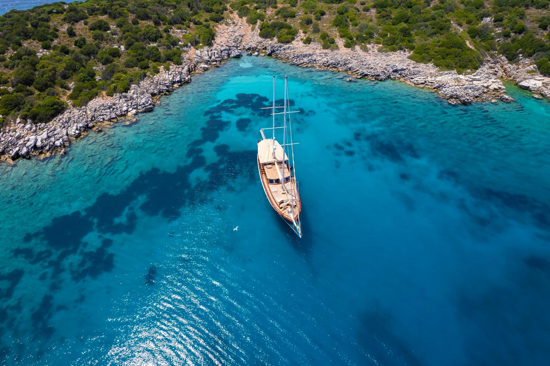 aerial view of traditional wooden gulet anchored in crystal clear turquoise Mediterranean bay