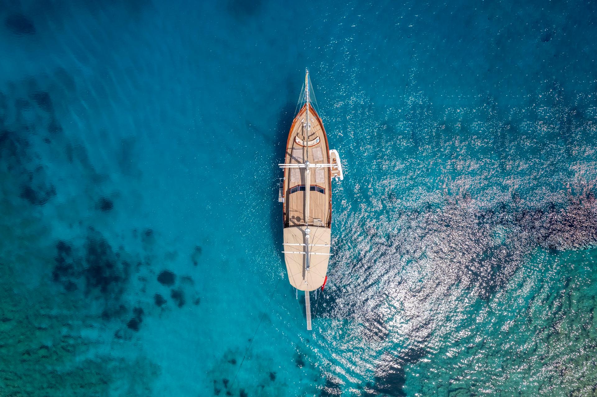 aerial view of traditional wooden gulet yacht anchored in crystal clear turquoise Mediterranean waters