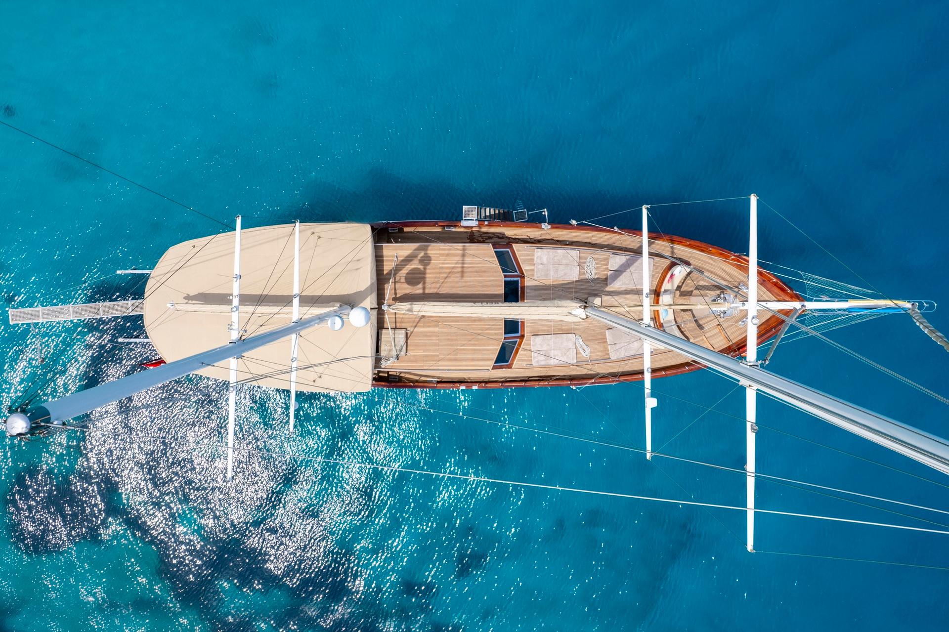 aerial drone view of traditional wooden gulet yacht anchored in turquoise waters