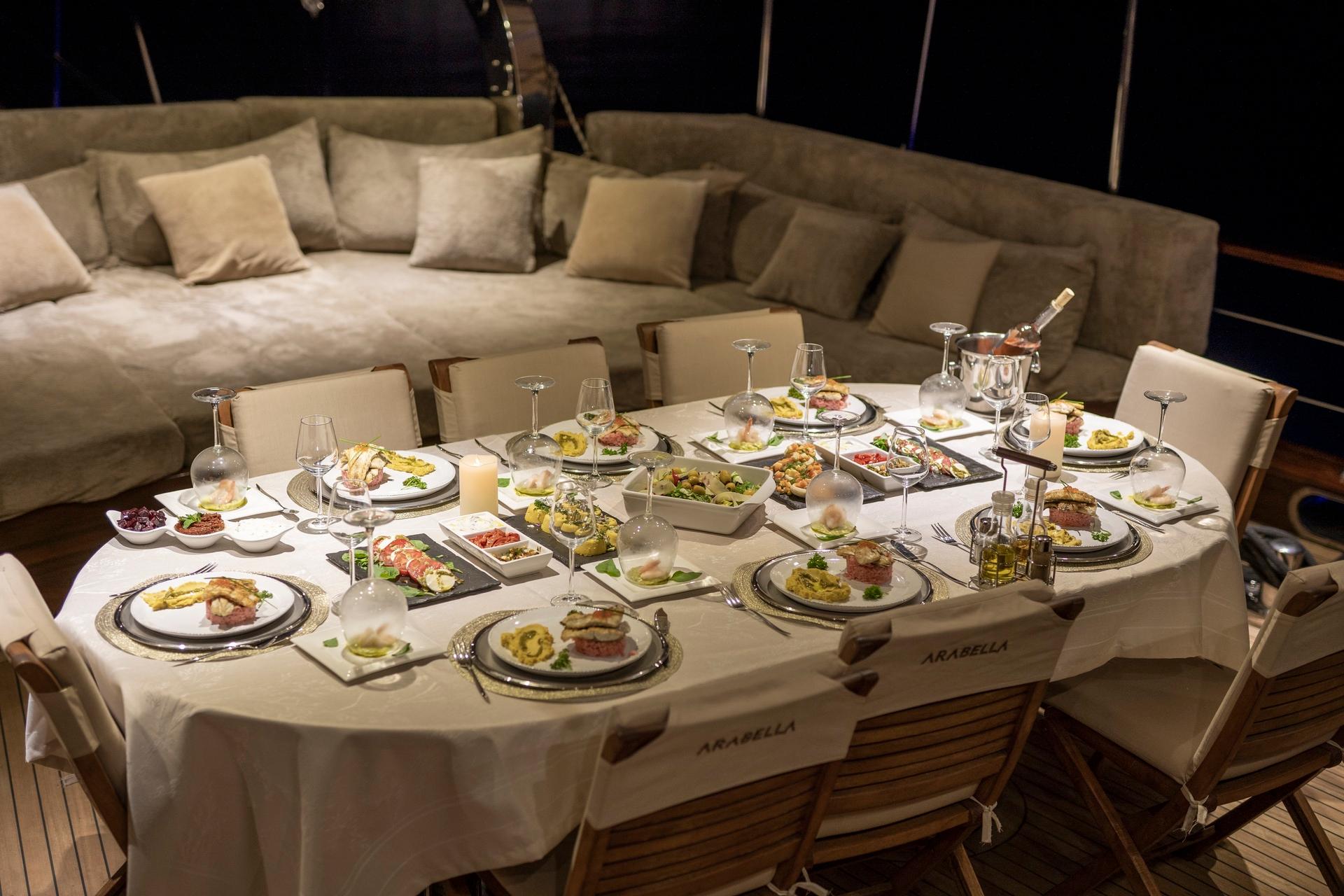 elegant yacht dining table with plated gourmet meals wine glasses and formal place settings