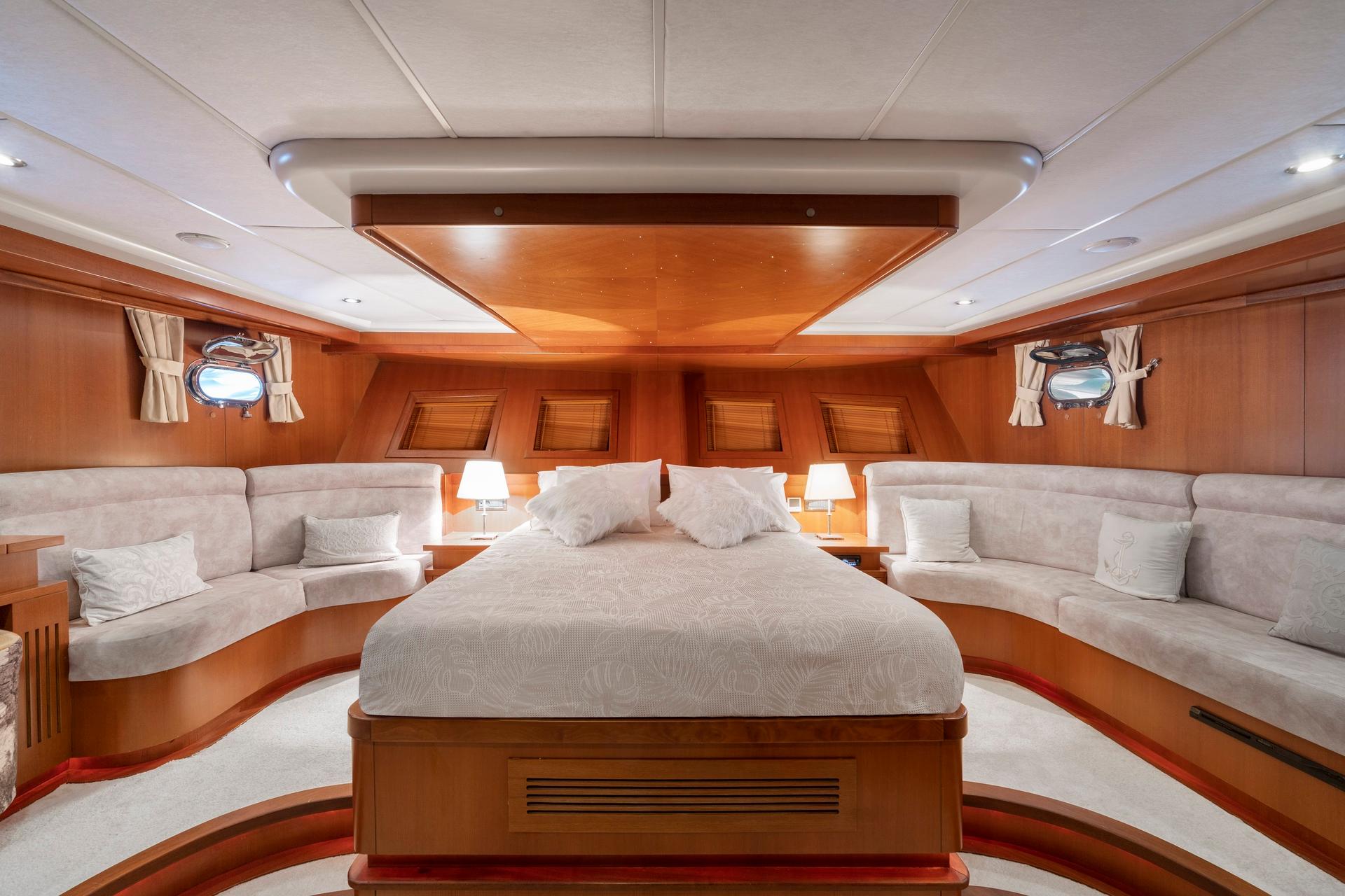 luxury yacht master cabin featuring king bed with white linens and built-in seating