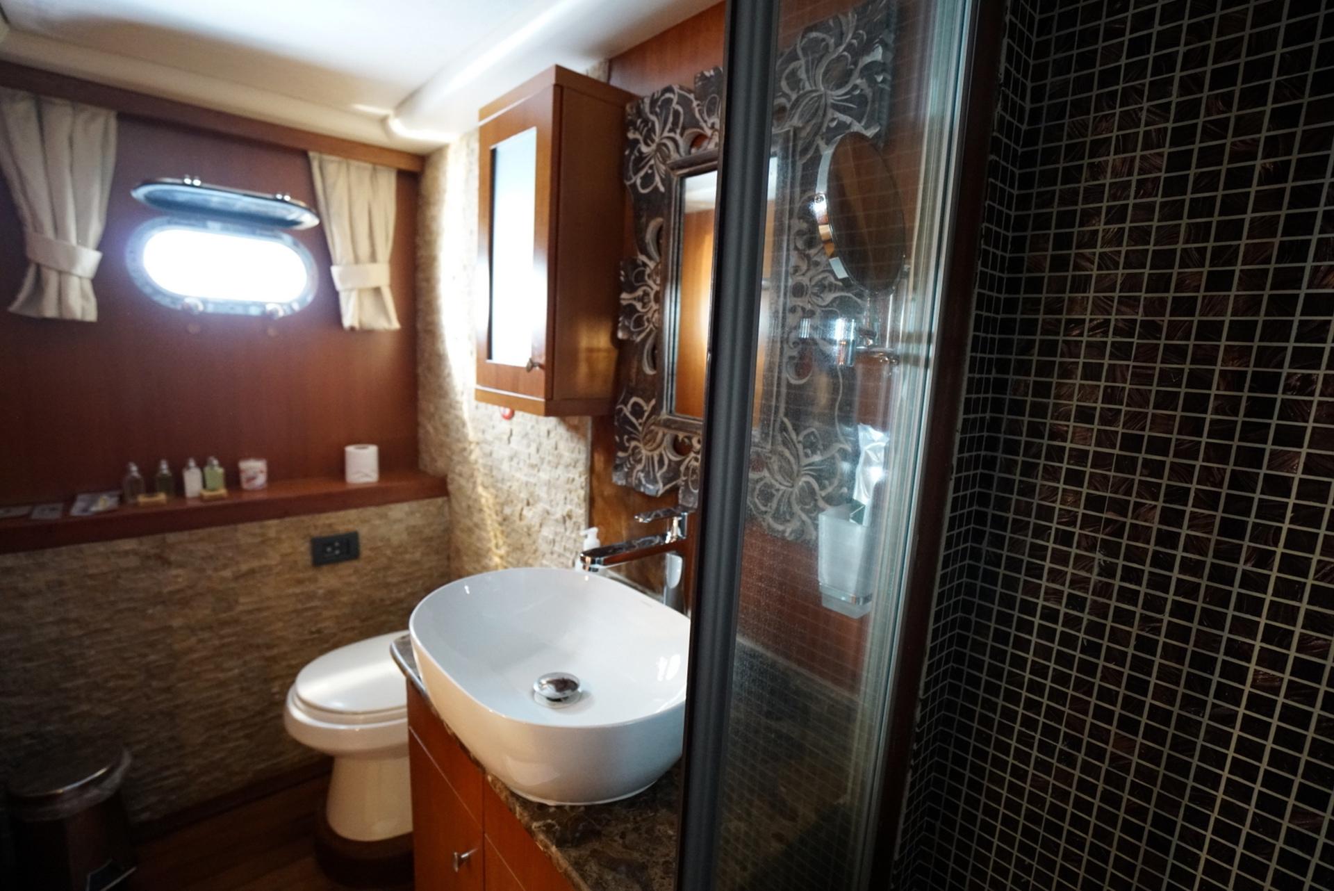 yacht bathroom featuring round vessel sink, glass shower enclosure with dark mosaic tiles
