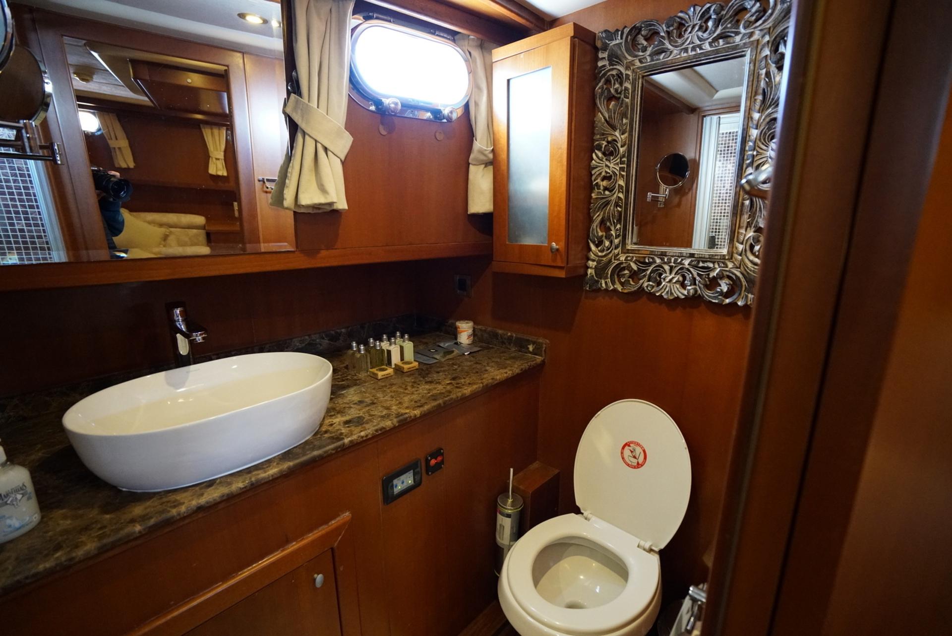 luxury yacht bathroom featuring white vessel sink, baroque mirror and wood paneling