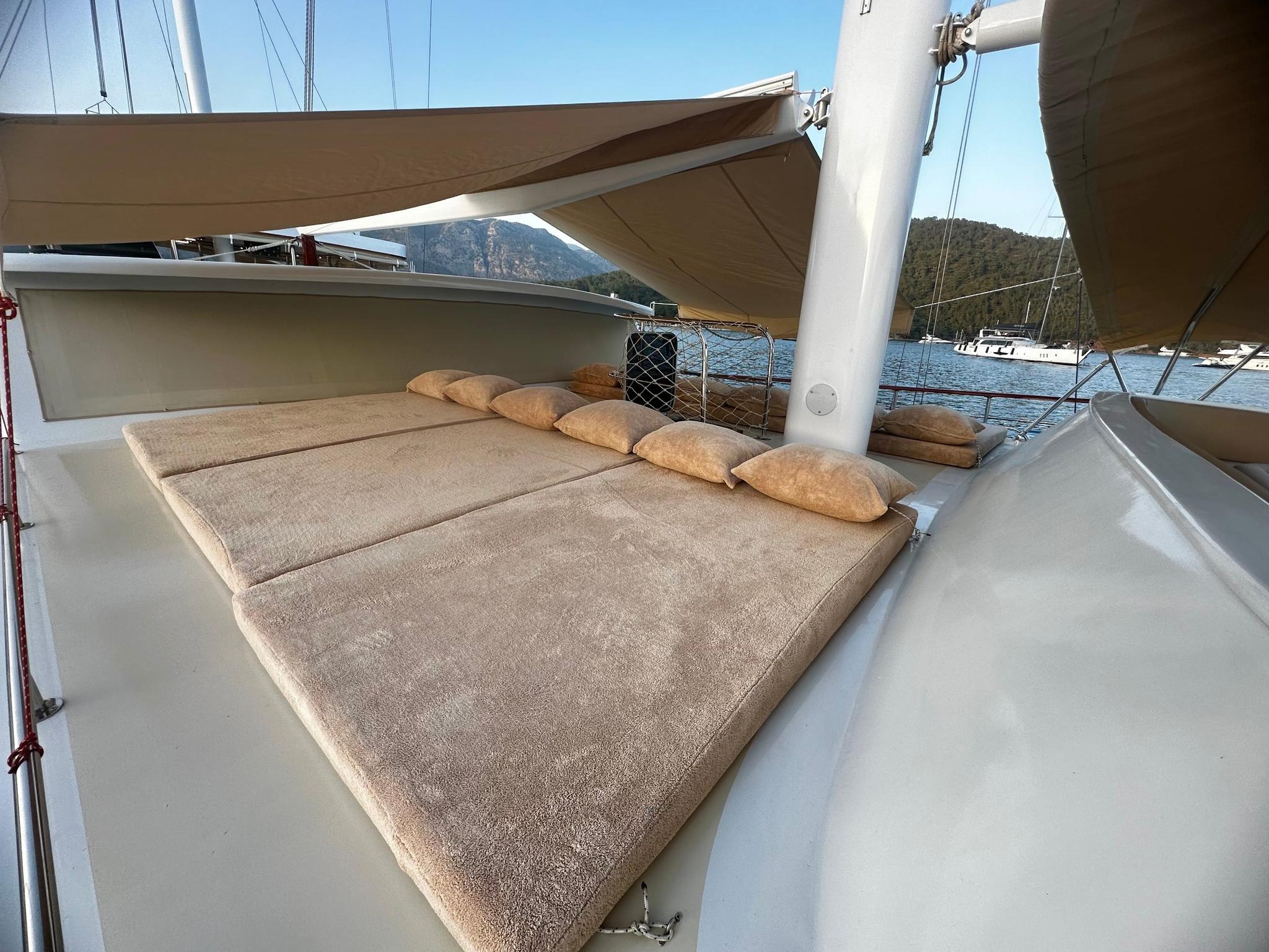 bow sun deck with beige cushioned loungers and canvas awning on luxury yacht
