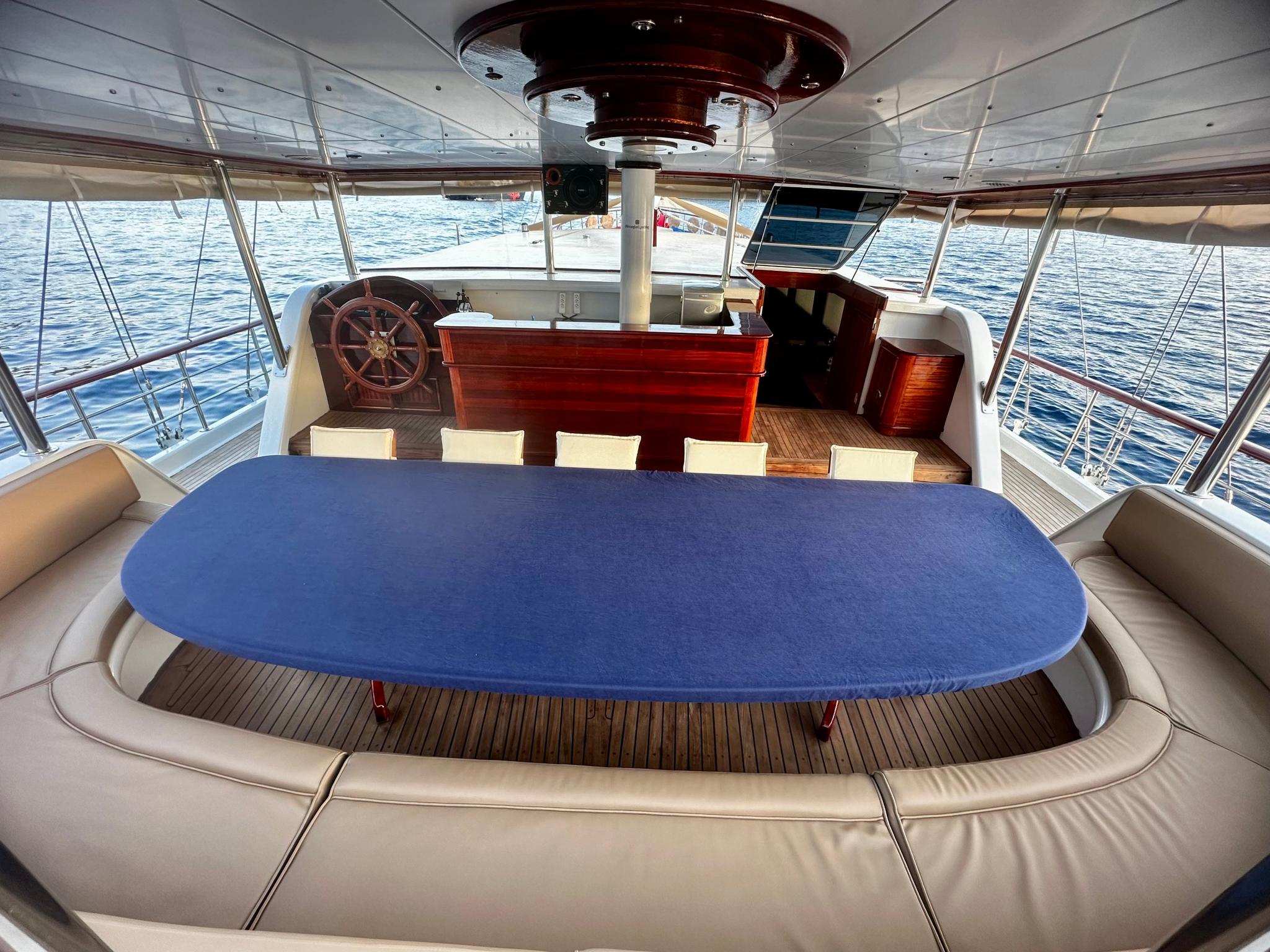 upper deck dining area with oval blue table cover and cream seating overlooking water
