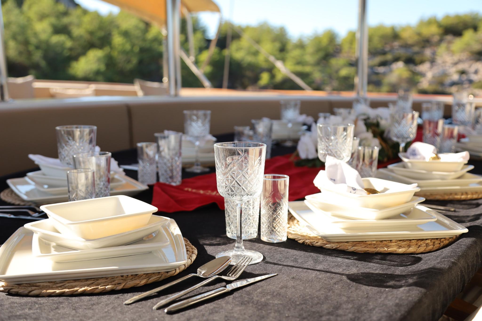 elegant yacht dining table with crystal glasses, white plates and red napkins
