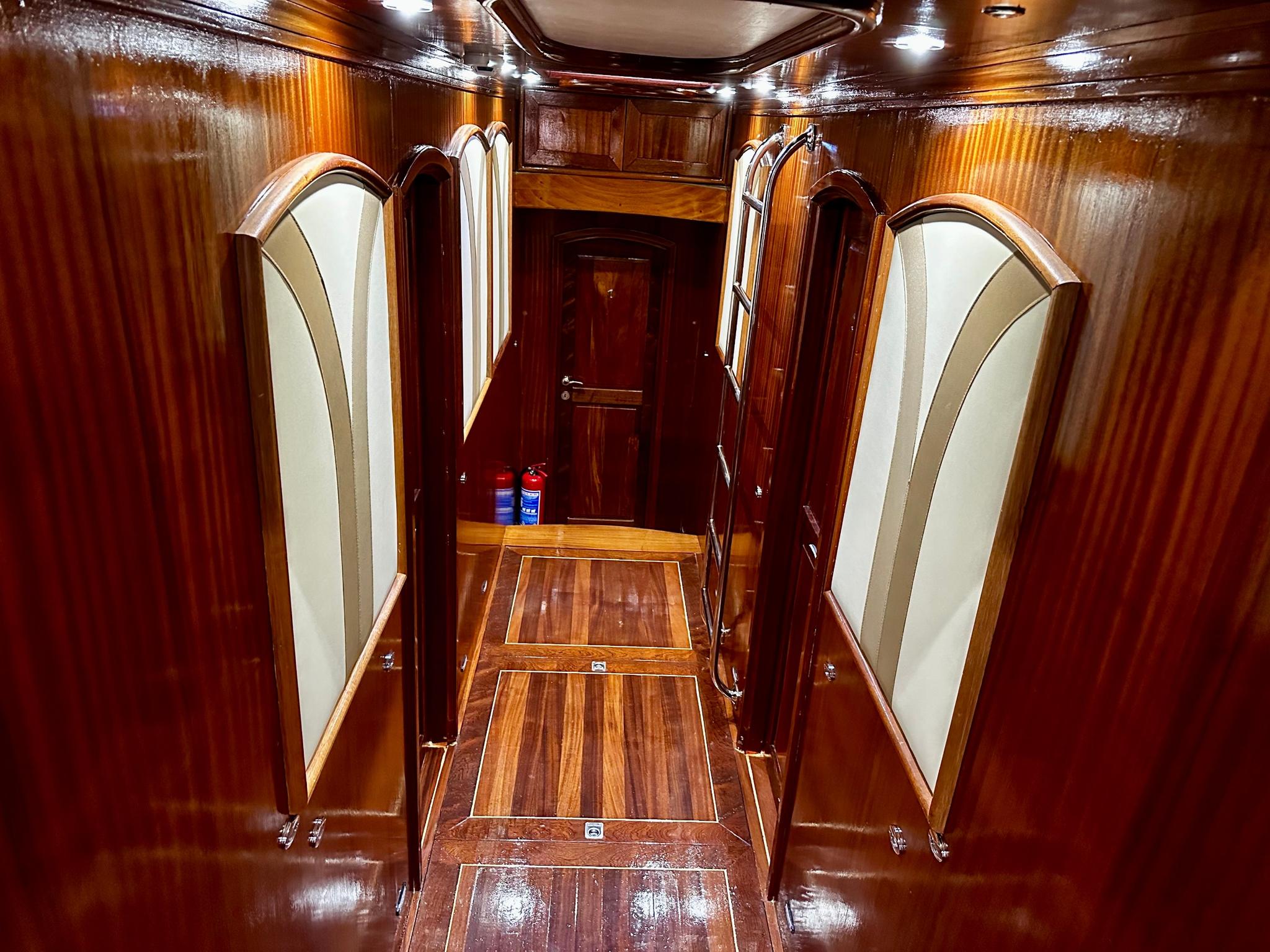 wooden companionway staircase leading down to guest cabin corridor with polished handrails