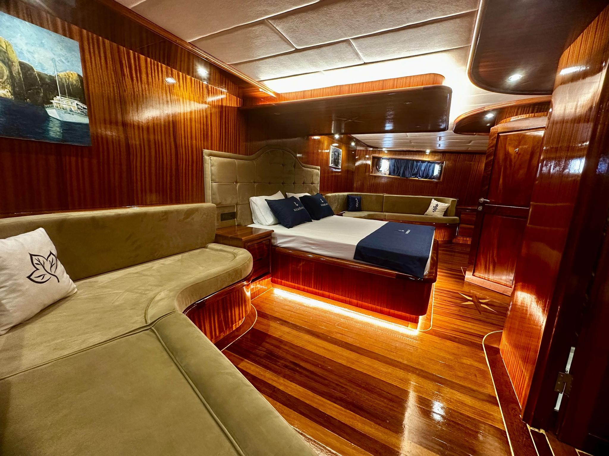 Master cabin with double bed, cream leather seating, polished wood paneling and entertainment system