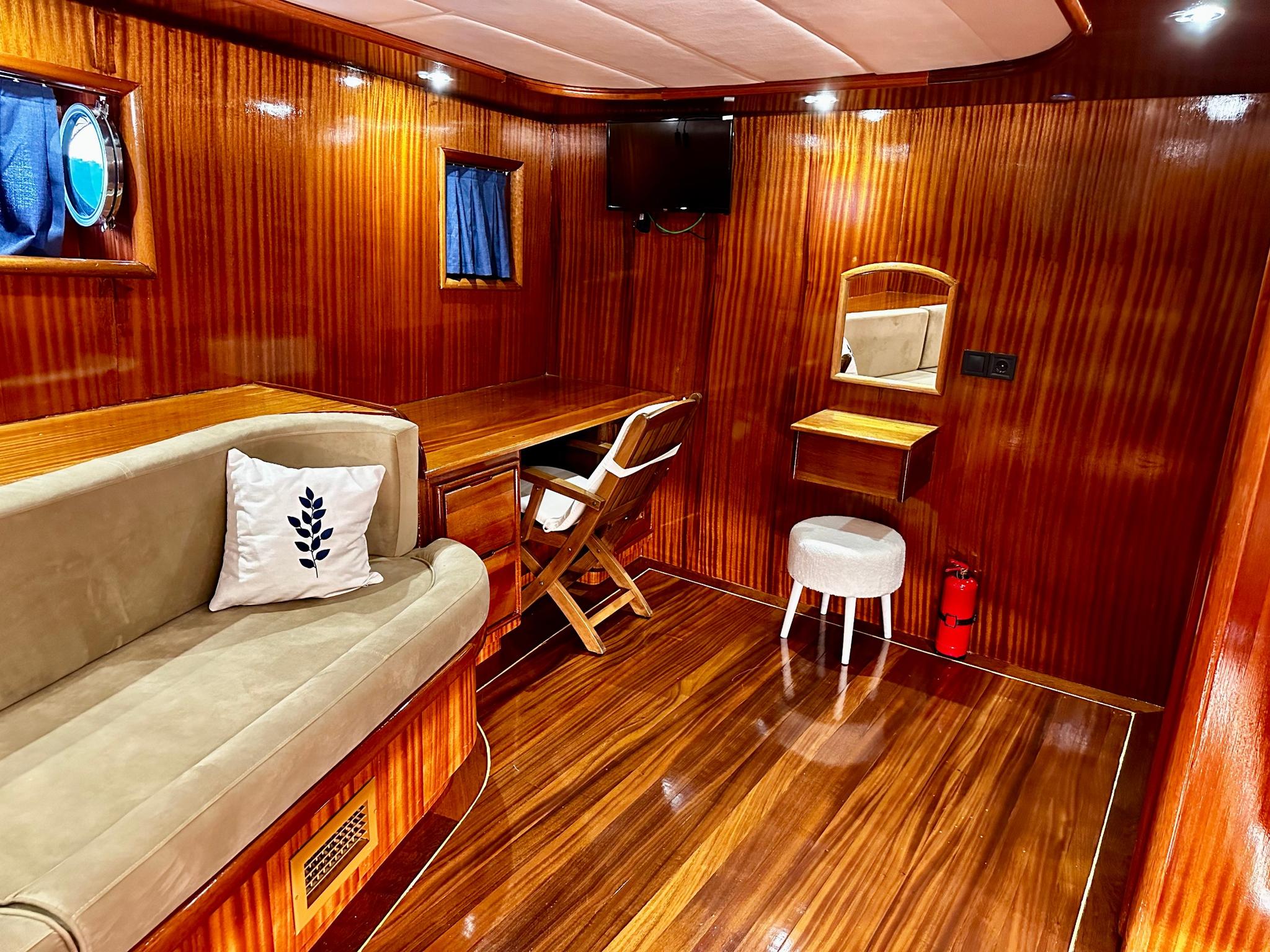 yacht cabin with beige sofa, wooden vanity table, mirror and warm wood paneling