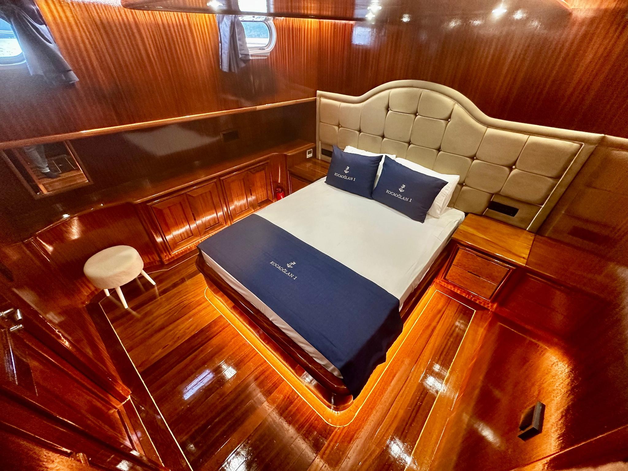 yacht guest cabin featuring double bed with cream tufted headboard and navy bedding